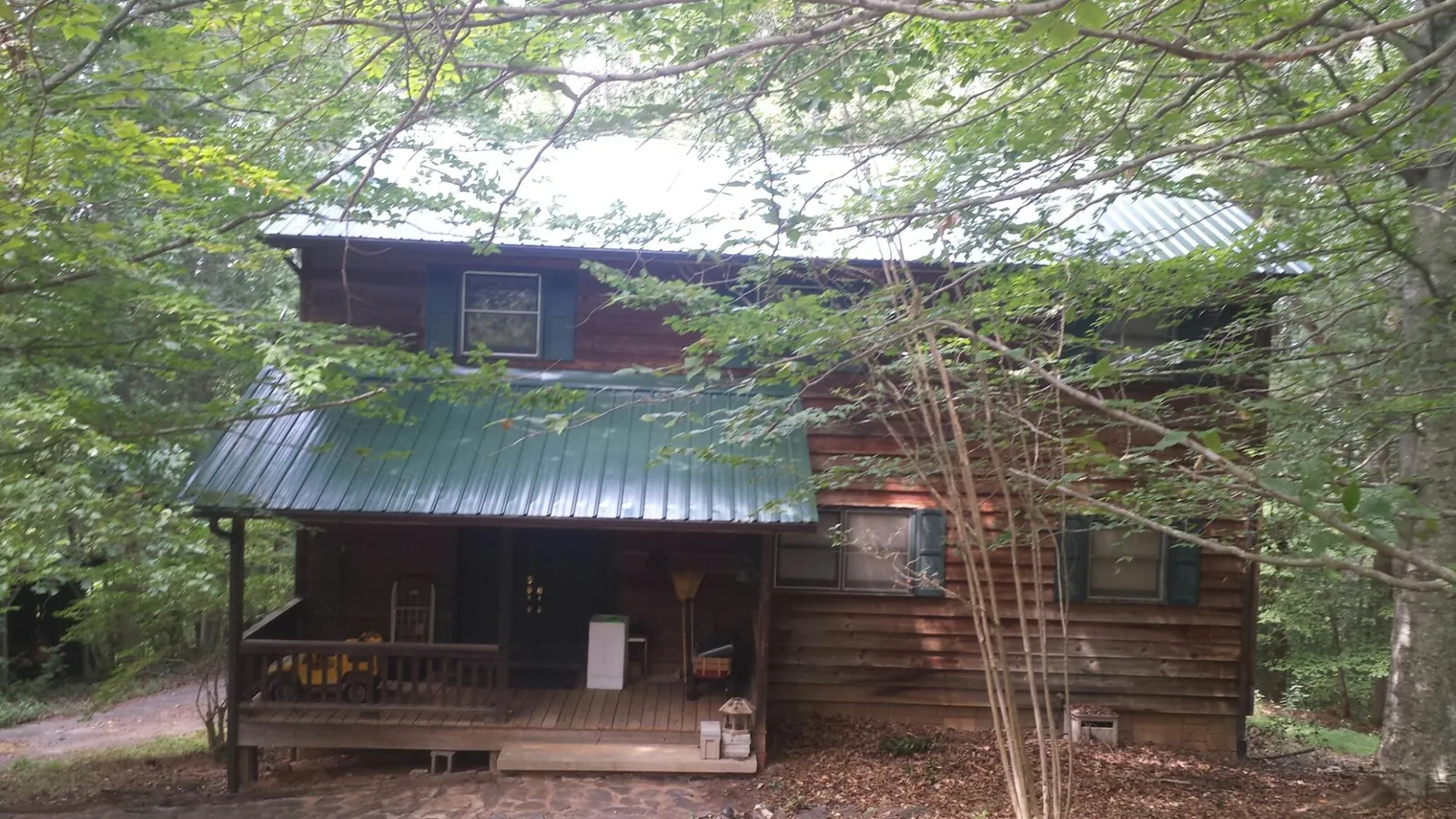 Green metal roof and covered porch on a log cabin in Forsyth