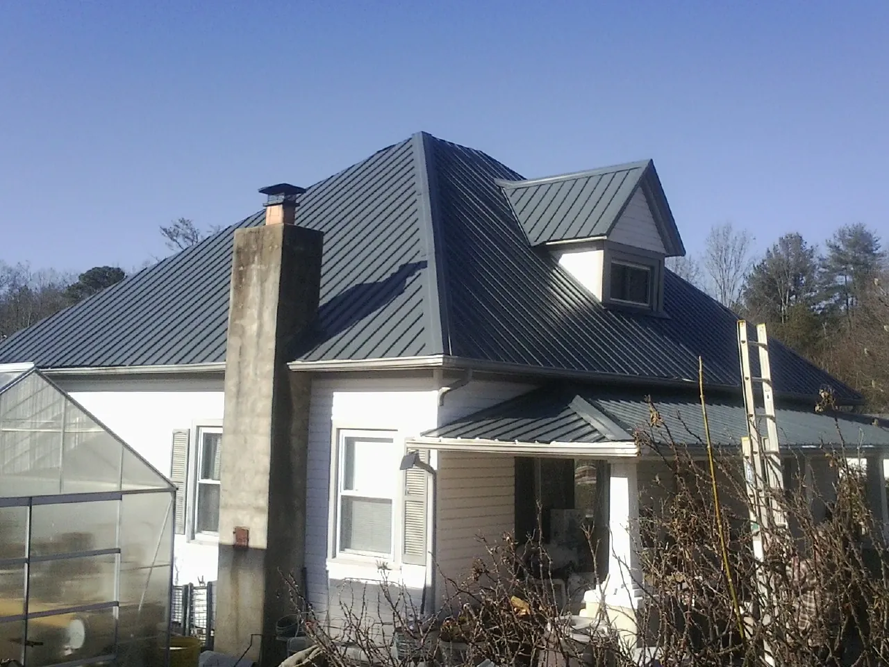 Dark blue standing seam metal roof on a white farmhouse with dormer — Slate & Tile Roof Repair by Roofing Brothers in Forsyth