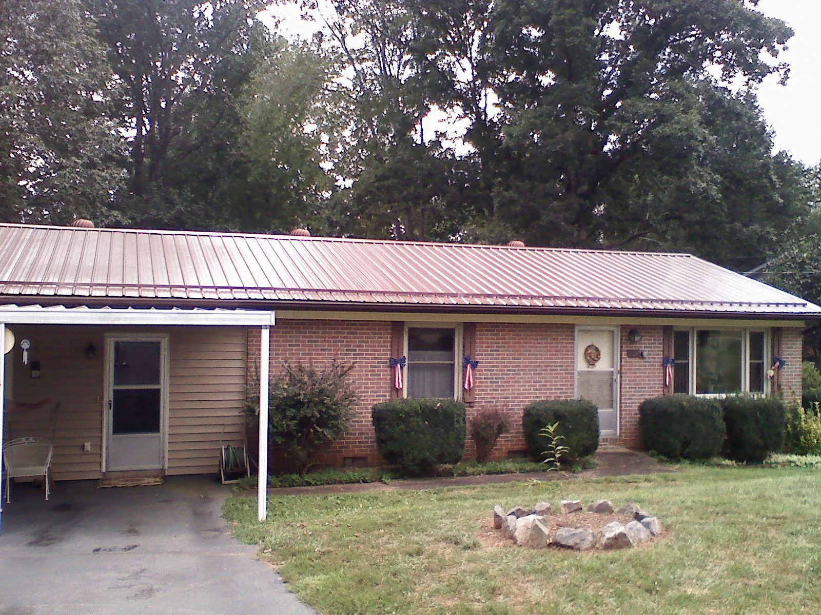 Bronze metal roof and carport on a brick ranch home — Roof Repair work by our crew in Forsyth